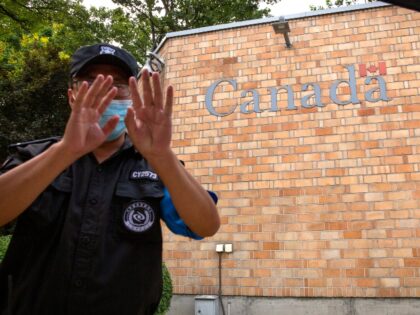 A security officer wearing a face mask to help protect against the coronavirus gestures ou