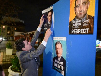 Mayor of Bucharest and presidential candidate Nicusor Dan pastes a campaign poster of hims